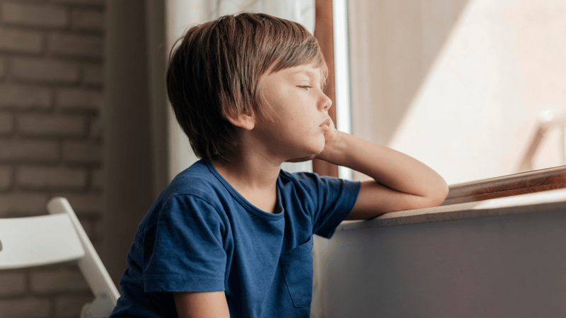 sad child looking out window
