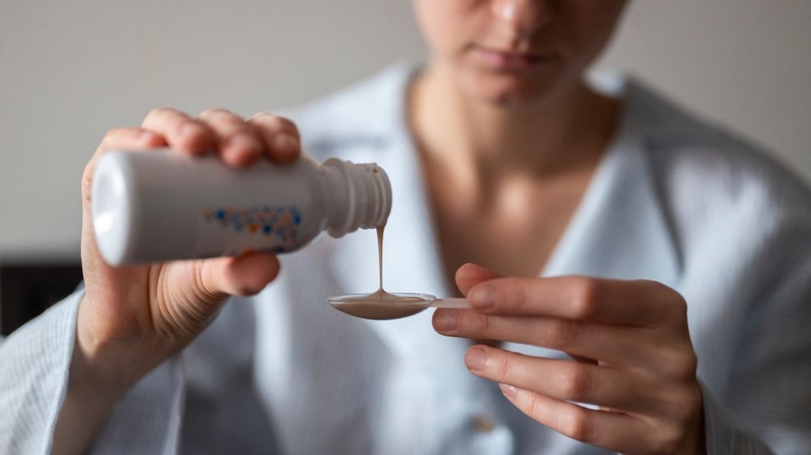 patient pouring cough syrup