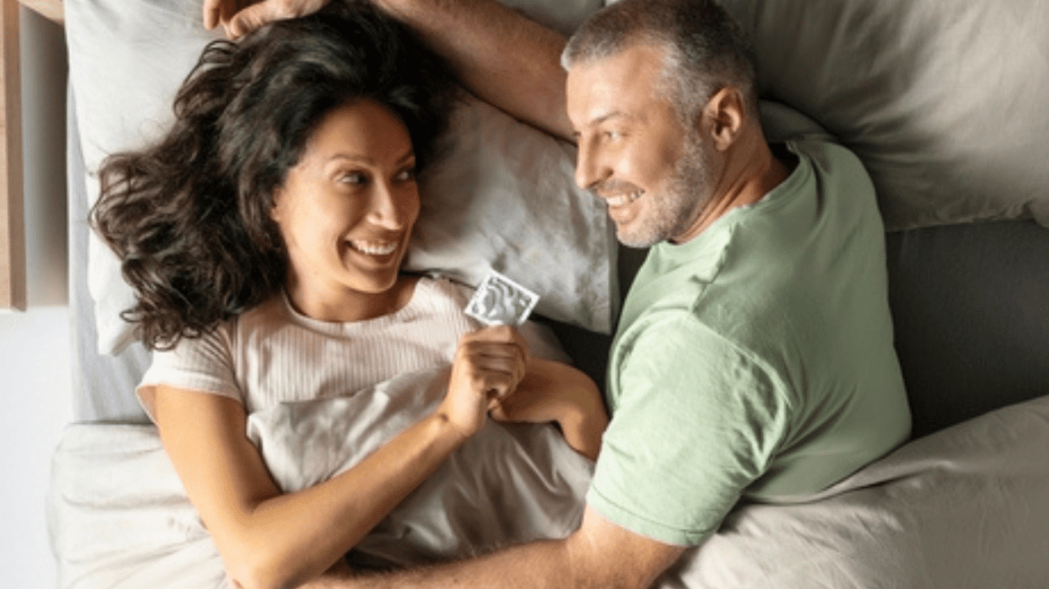 A man and woman lying down holding a condom