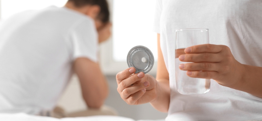 Couple in bedroom. Woman taking emergency contraception pill