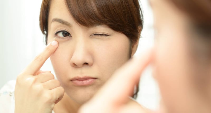 在鏡中看自己眼袋的女性