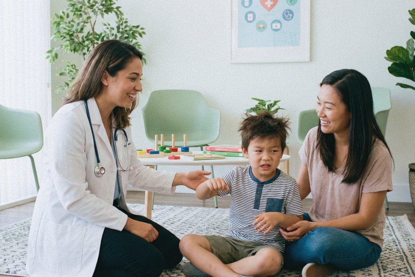 An Asian family (parent and child) where the child shows signs of behavioral issues like restless movements, in family therapy for parenting concerns with a mixed French-Asian specialist wearing a lab coat and stethoscope around her neck-1