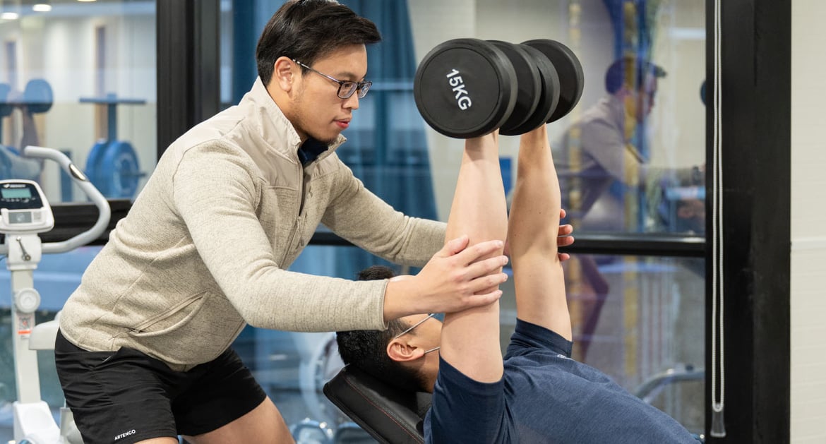 Physiotherapist training a patient in his arms' strength