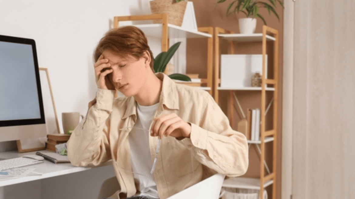 A tired young man sitting in front of the computer