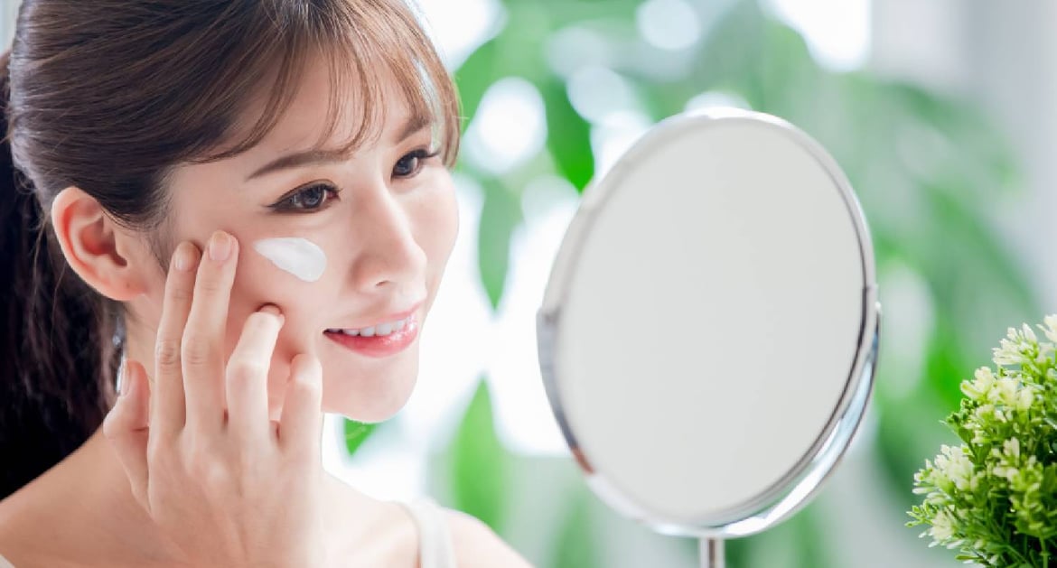 年輕女士在鏡前塗防曬霜