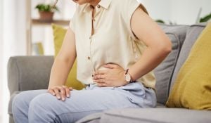 Sick Woman, Sofa and Stomach Pain for Health, Digestion and Nausea of Pms at Home. Closeup of Female Person, Menstruation and Abdomen Bloating of Constipation, Period and Endometriosis in Living Room