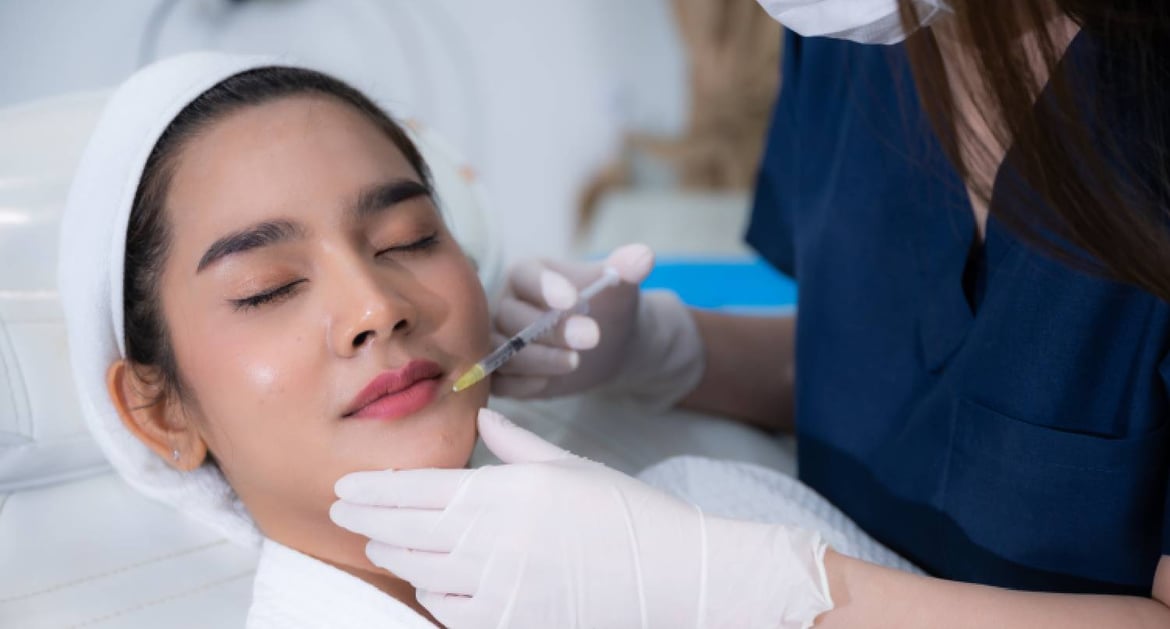 A doctor injecting botox into the lips of a young woman