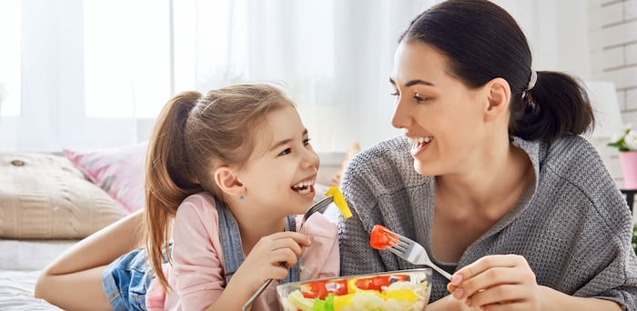 A mother feeding her daughter fruit