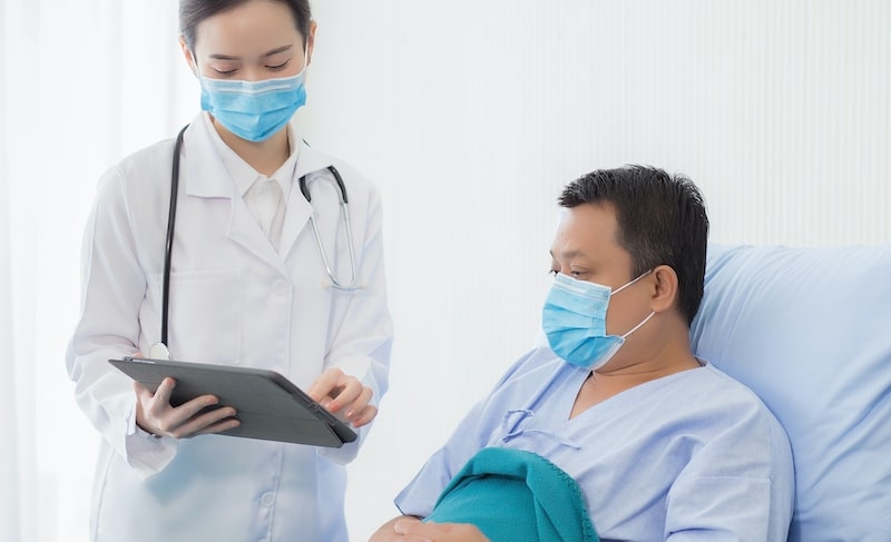 doctor explaining colonoscopy to patient in bed 