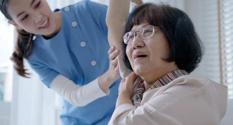 Physiotherapist training a patient in his arms' strength