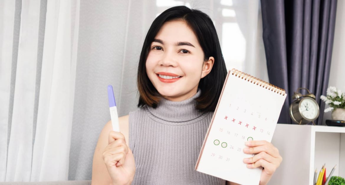 拿著驗孕棒和月曆的年輕女性