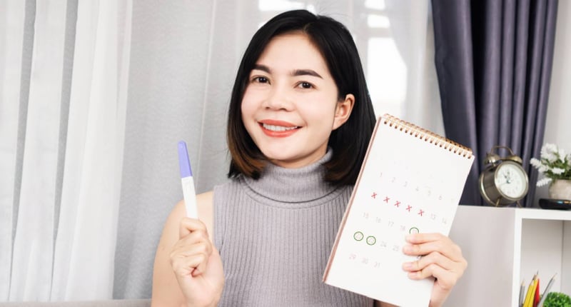 拿著驗孕棒和月曆的年輕女性