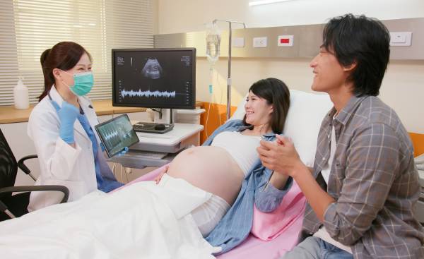 孕婦在丈夫陪伴下進行超聲波掃描