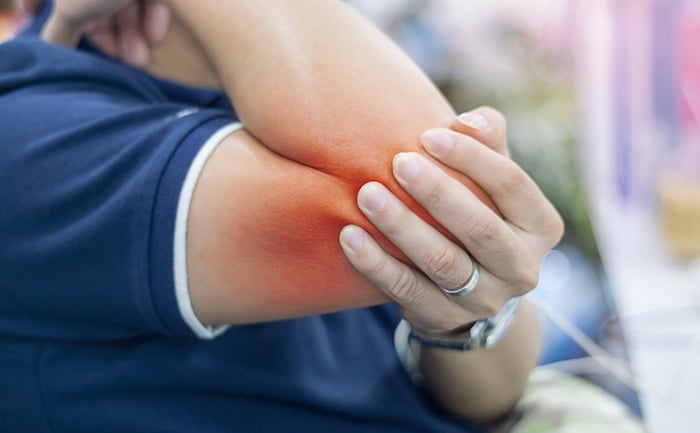 man scrunching elbow joint in pain