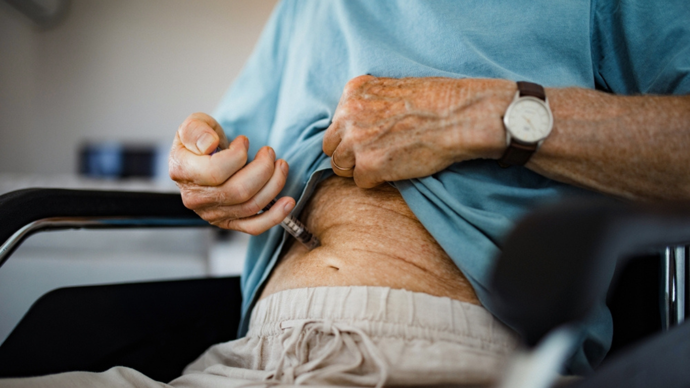 Diabetic senior patient injecting insulin in his belly.