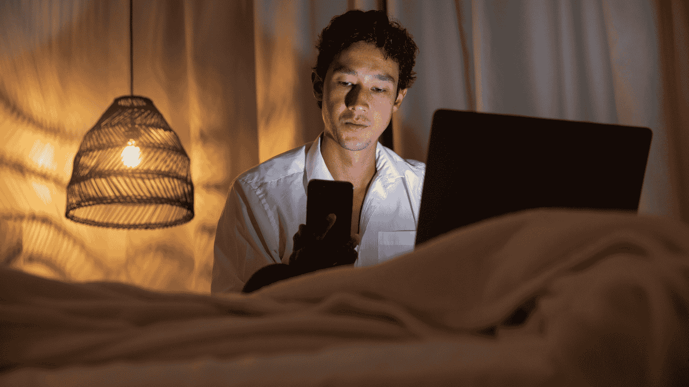 A man work with phone and laptop at night