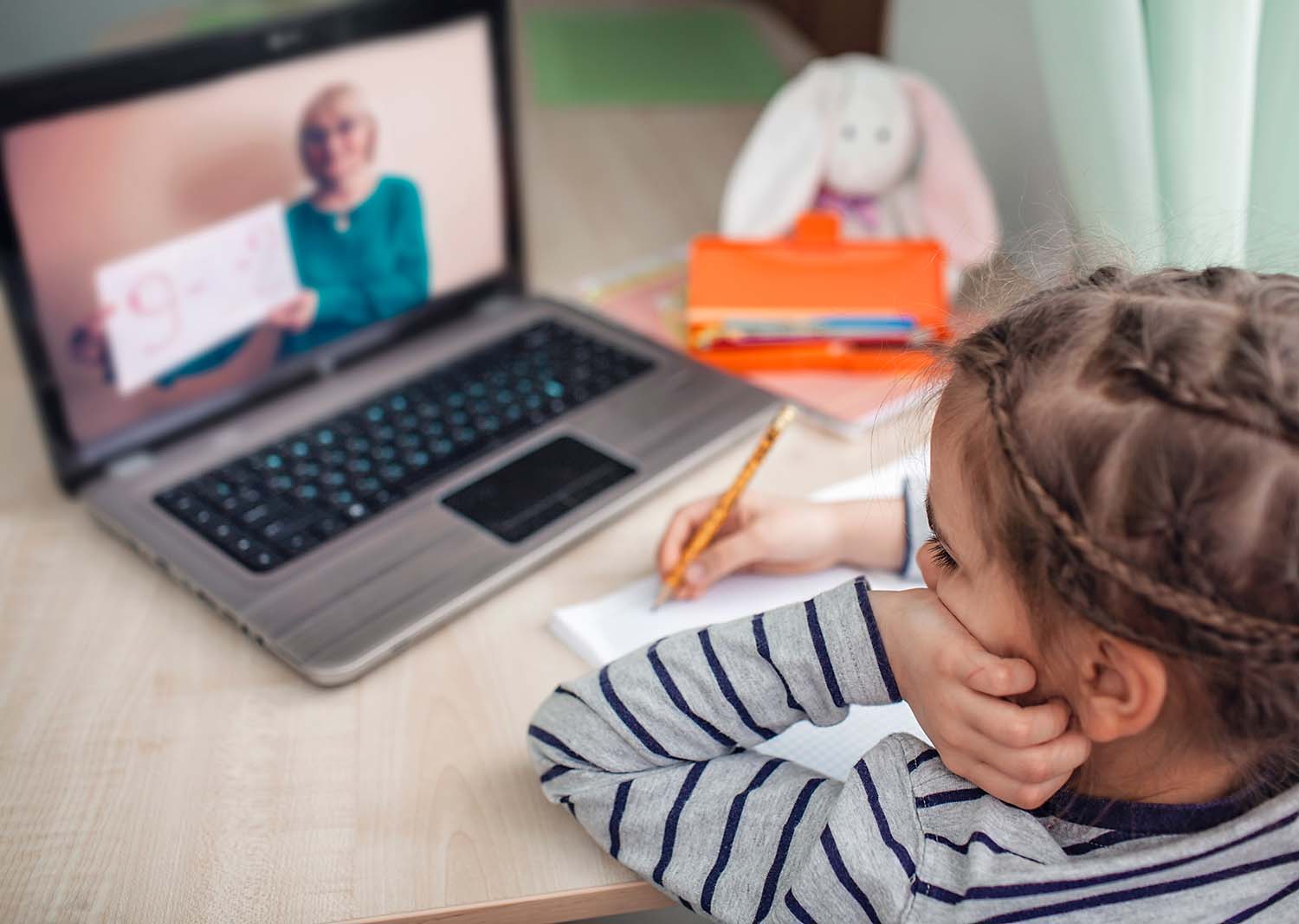 A young toddler attending an online session with her teacher