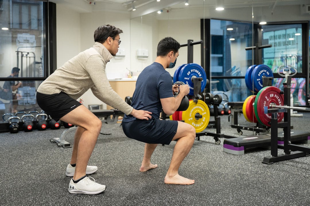Physiotherapist helping form for squat exercise