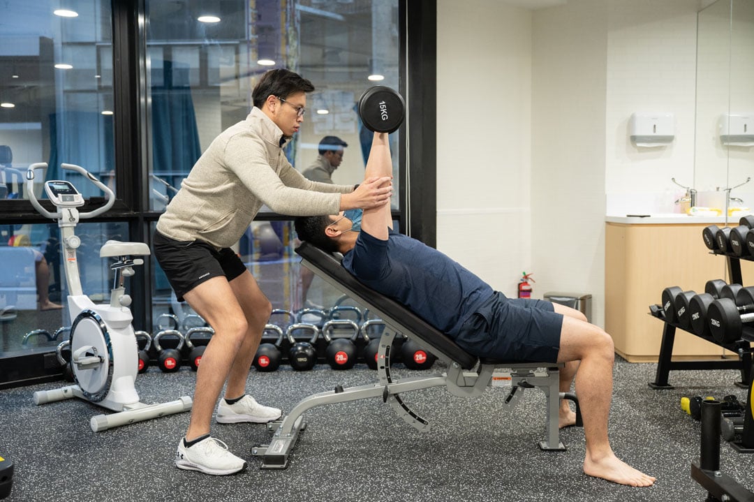Physiotherapist helping patient with chest press form