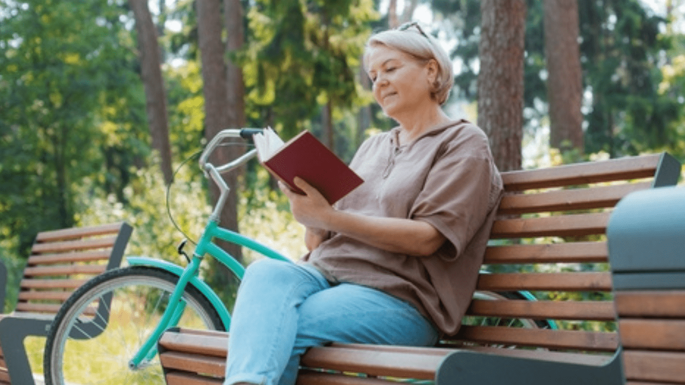 An old woman reading a book on the bench