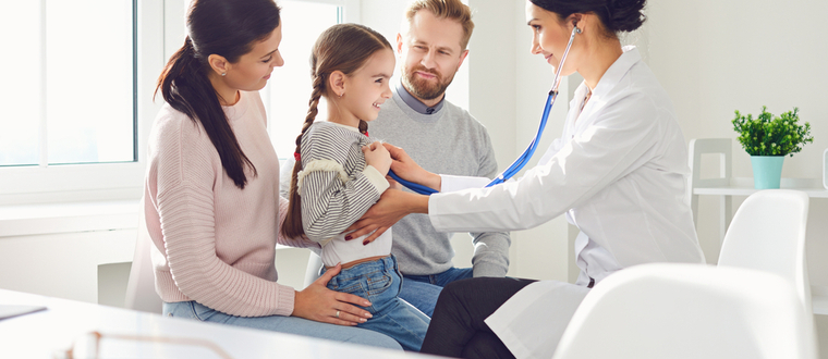 A female doctor performing a check up on a little girl while her parents watch.