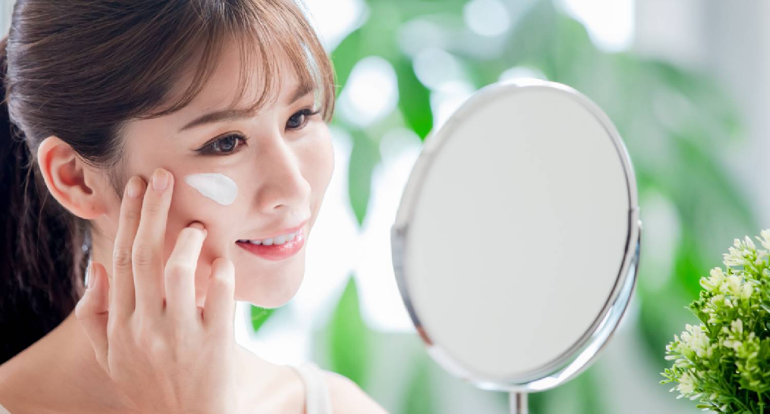 年輕女士在鏡前塗防曬霜