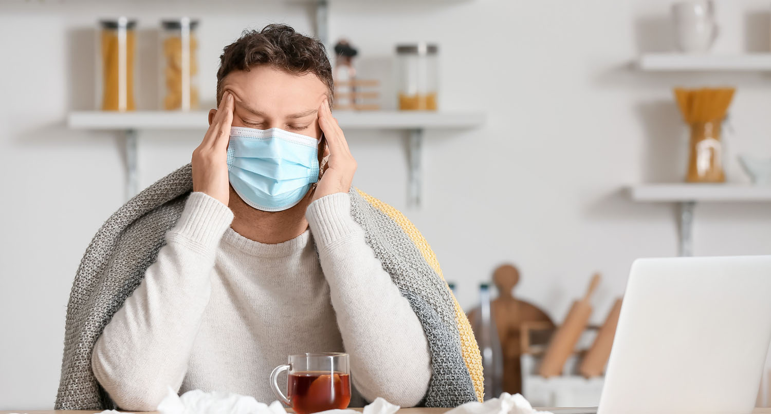 A young ill man suffers from a headache at home due to long COVID