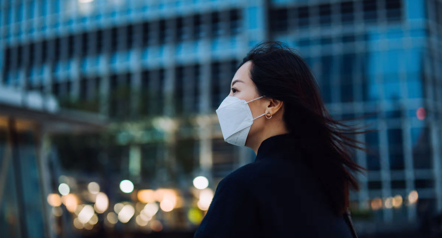 Woman at the rooftop of Hong Kong IFC and wearing a mask.