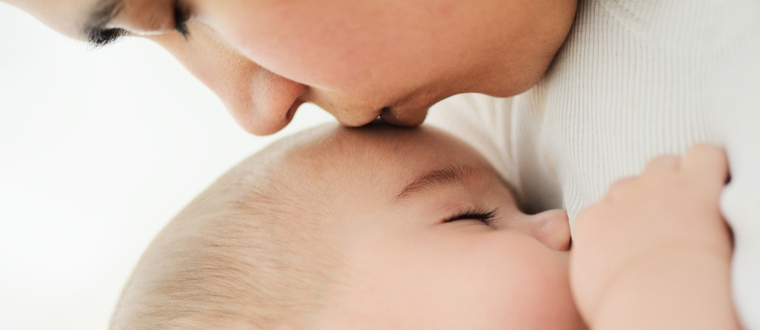 mother kissing newborn