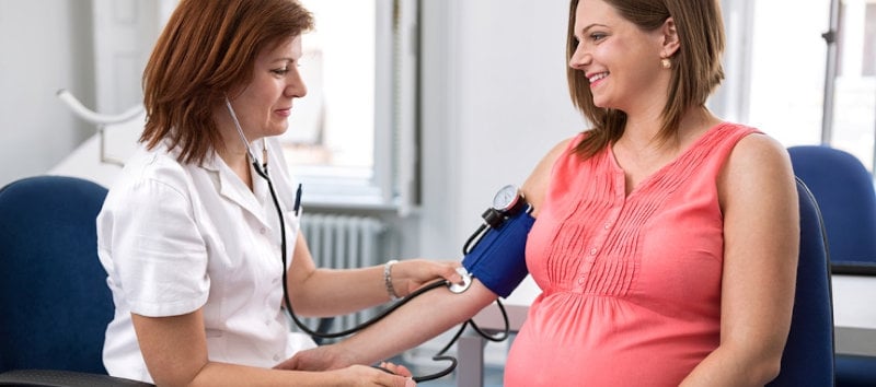 Midwife checking blood pressure of pregnant woman