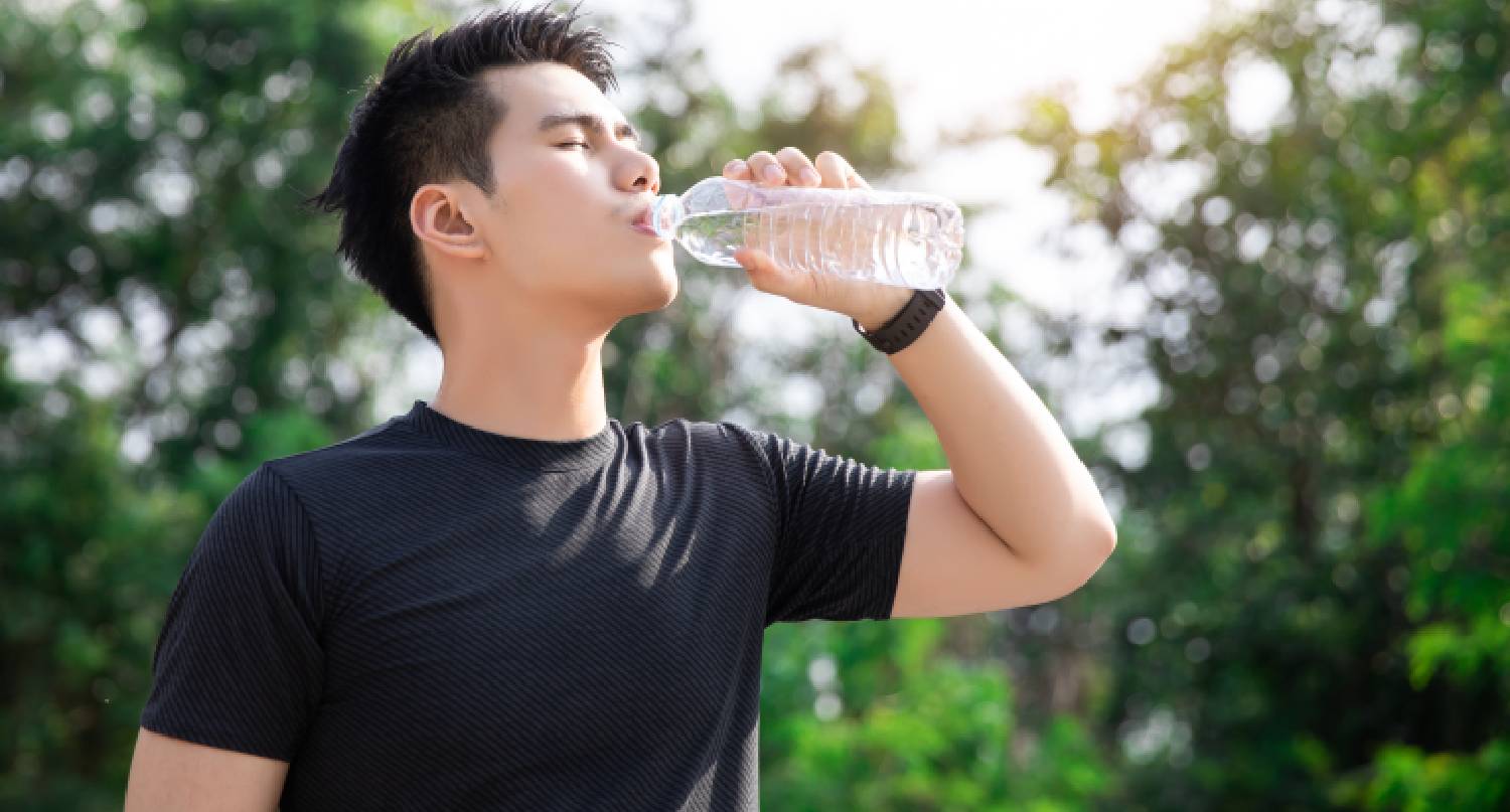 年輕男子在郊外喝水