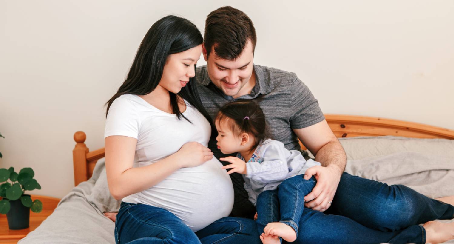 父親抱著女孩與懷孕的母親互動